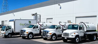 Four branded GeoGreen Biofuels trucks outside an industrial building