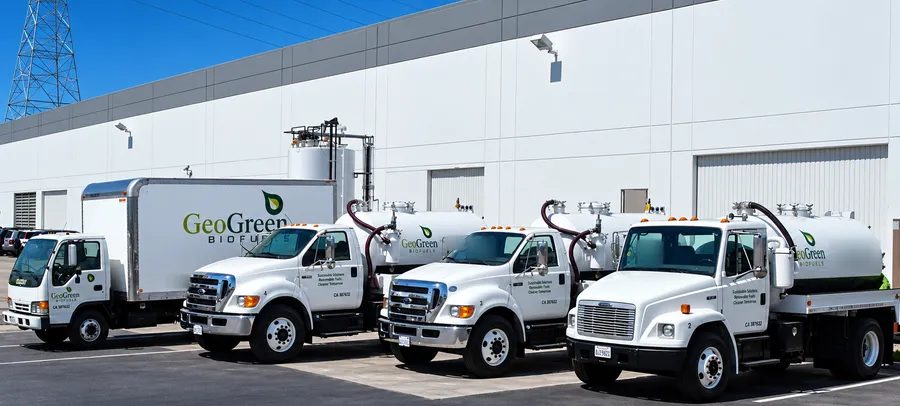 Four branded GeoGreen Biofuels trucks outside an industrial building