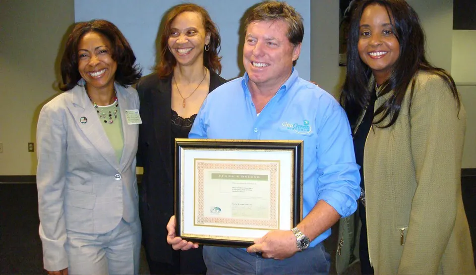 Holden Forrest in a GeoGreen Biofuels shirt holding a framed Certificate of Appreciation, with three other people beside him