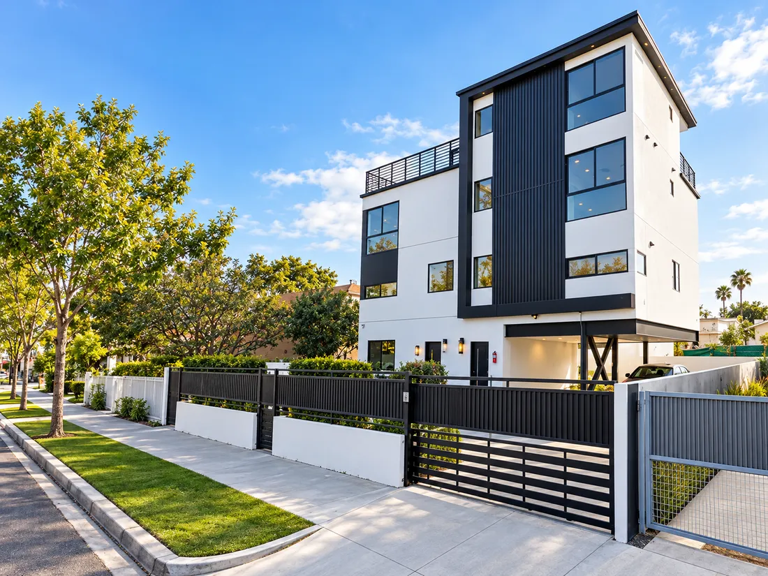 Modern three-story duplex with large windows, dark vertical cladding and a gated frontage